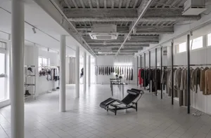 A modern retail shop featuring a concrete ceiling and clothing racks.