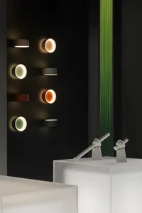 Multiple metal wall-mounted lights of varying colors displayed on a black wall.