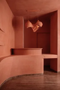 A modern minimalist concrete interior design with a unique hanging lamp and curved seating area.