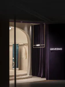 A modern retail space featuring purple curtains, a white display cabinet, and a white clothing garment hanging on a rod.