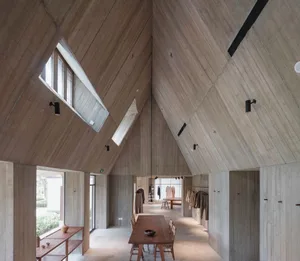 Concrete room with industrial design elements, featuring high ceilings, large windows, and a wooden dining table.