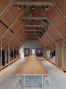 A minimalist clothing shop with wooden elements and a sloped, wooden ceiling structure.