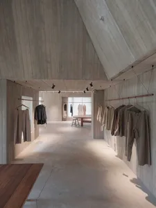 Minimalist clothing retail store with concrete walls and clothing racks.