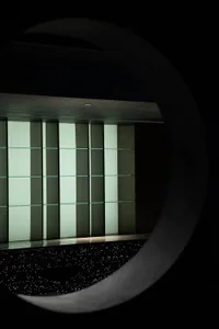 A modern black circular window displaying illuminated glass shelves.