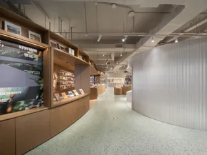 A spacious, modern bookstore interior with wooden shelves and concrete flooring.