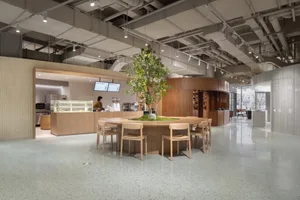 Modern coffee shop interior featuring a round table with a central tree and sustainable design elements.