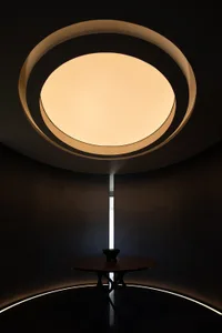 A minimalist concrete interior with a circular skylight providing diffused natural light.