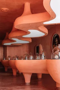 A modern shopping center with orange cement walls and lights.