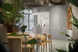 Modern industrial coffee shop with wooden furniture and green foliage.