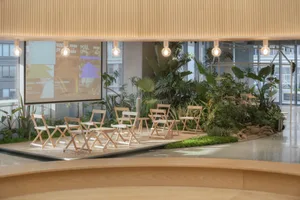 An industrial-style coffee shop with wooden furniture and greenery on a stage-like platform.