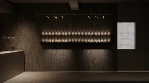 A minimalist industrial exhibition space featuring a brick wall, illuminated by track lighting.