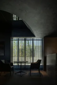 Industrial-style lobby with minimalist design and concrete materials, featuring a round table and two chairs.