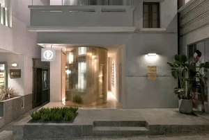 The entrance to a modern hotel, featuring glass walls and concrete flooring.