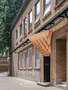 A modern building exterior featuring brick, concrete, and wood materials.