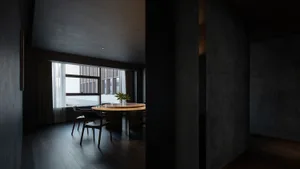 Interior photograph of a modern dark dining room with dark wood flooring and a round table.