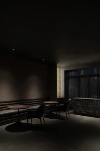 A sleek, dark-themed hotel lounge with modern furniture and dark stone finishes.