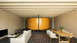A modern living room features a round wooden structure, white furniture, and minimalistic design.