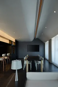 A modern office meeting room featuring a glass-topped conference table, white leather chairs, and concrete flooring.