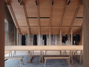 An interior of a showroom with wooden furniture and clothing racks.