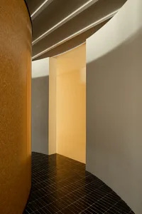 A minimalist interior space with sandblasted concrete walls and a dark tiled floor.