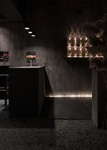 Dark, modern, concrete-themed restaurant-bar interior with minimalist design elements and warm lighting.
