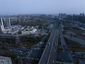 Aerial view of a cityscape featuring a modern highway system with concrete, steel, and glass elements.
