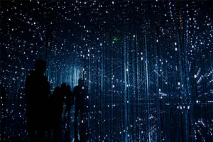 A nighttime scene featuring an interactive light installation with thousands of hanging lights suspended from the ceiling. Vi