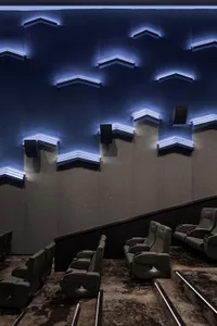 Industrial-style cinema interior with textured concrete walls and modern, ergonomic seating.
