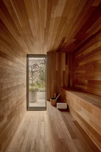 A wooden sauna room with a window showing a view of the outdoors.