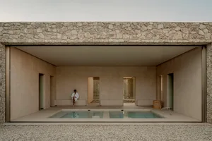 A minimalist swimming pool with concrete walls and floor, featuring a person relaxing in a white robe.