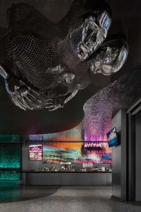 A modern cinema lobby featuring metallic sculptures, glass panels, and LED lighting.