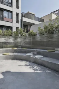 Modern garden space with circular seating area, concrete walls, and greenery.