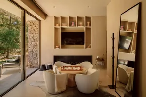 A modern living room with a neutral color palette featuring comfortable seating, a fireplace, and decorative shelves.
