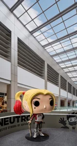 A large, plastic Harley Quinn figurine from the Funimation Pop collection is displayed in a shopping center with a modern int