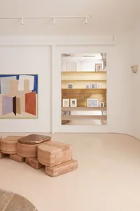 現代極簡藝術畫廊，木質與金屬展示架陳列著裱框藝術作品。
