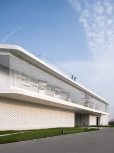 Modern architectural building with transparent glass facade and white perforated wall