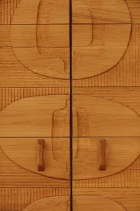 Close-up view of a modern wooden sideboard featuring geometric patterns and wooden handles.
