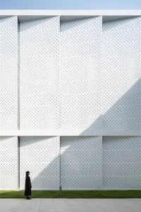 A modern building facade featuring a white perforated metal panel