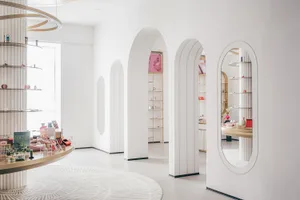 A modern retail space featuring minimalist design, white archways, and white walls with display shelves.