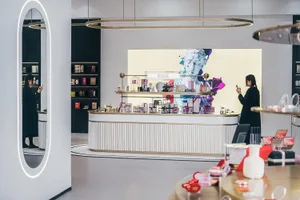 A modern minimalist retail storefront interior with a sleek white and gold color scheme, showcasing various beauty products.