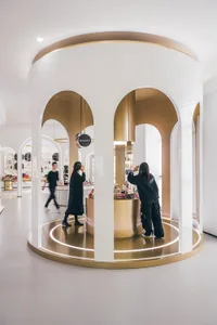 People interacting with cosmetic products at a modern retail store with minimalist gold accents.
