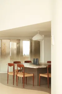 A modern dining room featuring a marble table with wooden chairs and a pendant light hanging above.