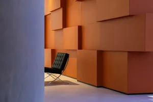 An elegant, modern interior space with a striking, orange-leather accent wall and a sleek, contemporary chair.