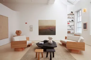 A modern living room featuring wooden furniture, a fabric sofa, and a textured rug.