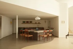 A minimalist kitchen featuring a granite dining table surrounded by wooden chairs.