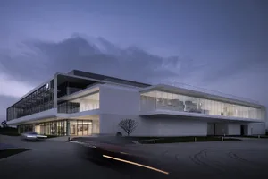 A contemporary building with glass facade and concrete elements at dusk