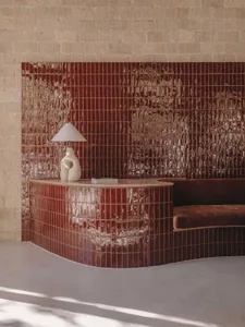 A modern living room featuring ceramic tiles, a curved seating area, and a unique table lamp.
