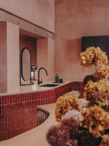 A minimalist bathroom featuring red ceramic tiles and black fixtures