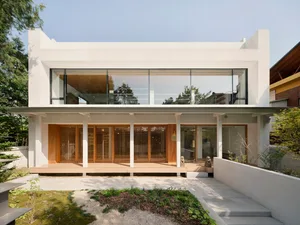 Modern minimalist house with white stucco exterior, large glass windows, and wooden accents.