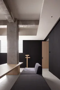 A minimalist residential interior featuring concrete and wood materials.